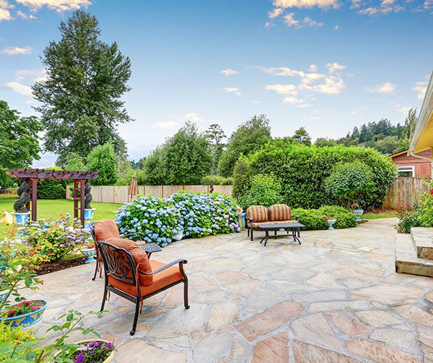 Well-designed backyard patio with chairs and flowering plants